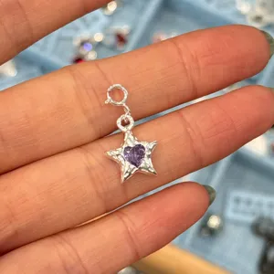Nahaufnahme eines 925er Silber Sternanhängers mit einem lila Herz-Zirkonia