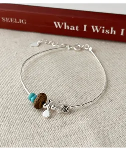 Nahaufnahme eines S925 Silberarmbands mit Adlerholz und synthetischen Türkisperlen