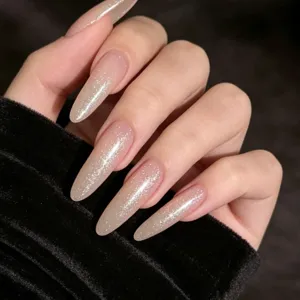 Close-up of shimmering glitter top coat on long nude stiletto nails over black velvet