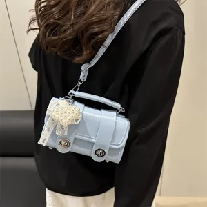 Elegante bolso bandolera azul claro de mujer con dije de perlas y cierre metálico moderno.