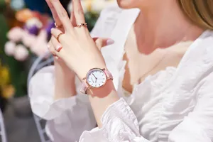 Detailopname van een elegant dameskwartshorloge met roze leren bandje om de pols van een model