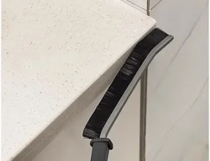 Detail view of the long handle crevice brush cleaning narrow gaps and tile corners easily.