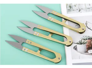 Detail view of U-shaped spring thread scissors, golden metal handle for sewing craft.