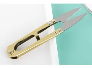 Detailed close-up of U-shaped thread scissors with gold handle for sewing and embroidery.