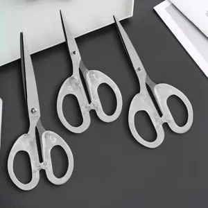 Close-up detail view of transparent handle stainless steel craft scissors on dark surface.