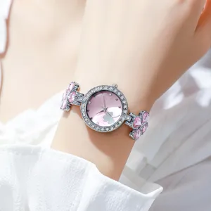 Detailansicht einer eleganten Damen-Armbanduhr mit rosa Kleeblatt und Straßsteinen