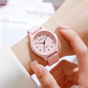 Dettaglio macro di un orologio analogico rosa minimalista con cinturino in silicone al polso.