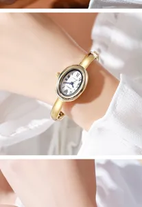 Primer plano de un elegante reloj de mujer ovalado dorado con números romanos en la muñeca