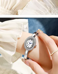 Nahaufnahme einer silbernen ovalen Damenuhr mit Strass-Lünette an einem Handgelenk