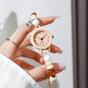 Primer plano de un reloj de cuarzo para mujer con correa de cuentas trenzadas de colores