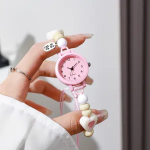 Primer plano de reloj rosa para estudiantes con cuentas de colores y correa trenzada