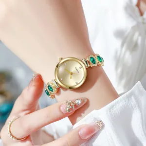 Vue détaillée d'une élégante montre-bracelet dorée pour femme avec pierres vertes