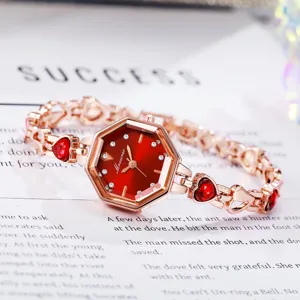 Vue rapprochée élégante d'une montre octogonale en or rose avec cadran rouge et cœurs