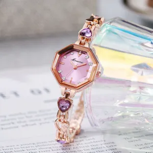 Gros plan d'une montre octogonale or rose pour femme avec pierres cœurs violettes et diamants.