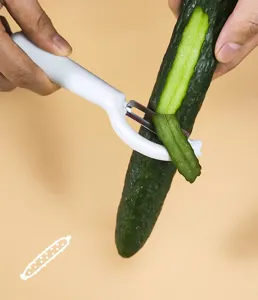Stainless steel vegetable fruit peeler detail showing kitchen tool peeling cucumber.