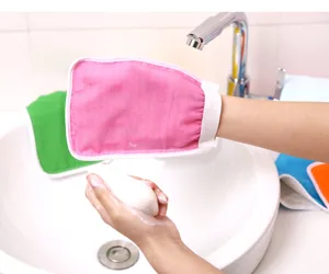 Exfoliating bath mitt detail view, showing pink double-sided scrubbing glove texture in use.