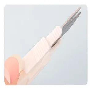 Close-up detail shot of white U-shaped embroidery yarn scissors with protective cap.