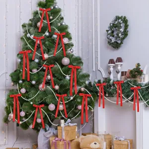 Primer plano de lazos de satén rojo y cadenas de perlas que decoran un árbol de Navidad.