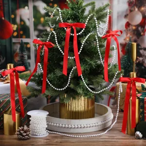 Árbol de navidad lazos de satén rojo y guirnalda de cuentas de perlas para fiesta.