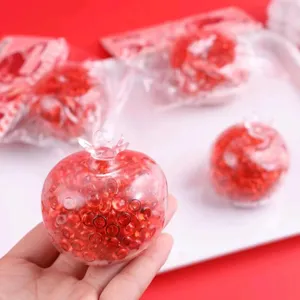 Close-up detail of transparent red pomegranate stress relief squeeze toy with beads inside.