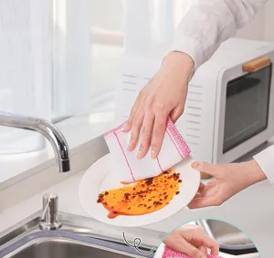 Detalle de paño de cocina que muestra una limpieza eficaz de aceite en platos con malla gruesa.