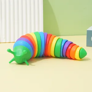 Close-up of a colorful rainbow articulated slug fidget toy on a yellow tabletop setting.