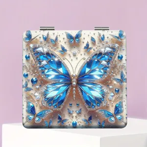 Quadratischer klappbarer Taschen-Make-up-Spiegel mit funkelndem blauen Schmetterlings-Design.