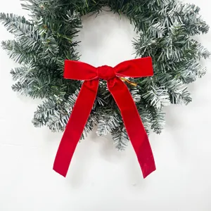 Close-up detail of the Christmas wreath featuring a vibrant red velvet bow and snowy pine.