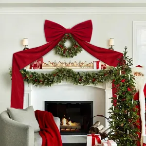 Extra large red velvet Christmas tree bow with long streamers, festive fireplace holiday decor.