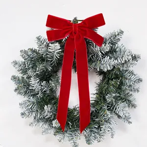 Christmas wreath detail close-up featuring snow-flocked pine branches and a red velvet bow.