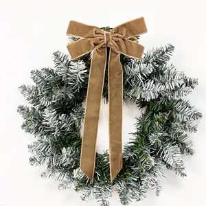 Christmas artificial frosted pine wreath with elegant brown velvet bow holiday decor detail shot.