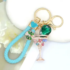 Detail view of metal rhinestone cocktail glass keychain with blue braided strap for backpack