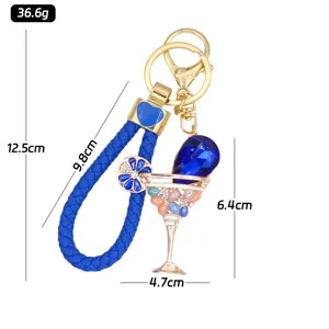 Detail view of a blue metal cocktail glass keychain with rhinestone and braided strap.