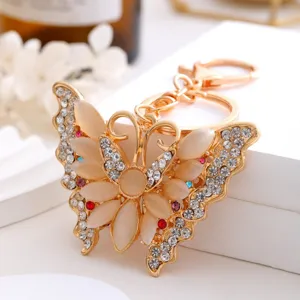 Gros plan détaillé d'un porte-clés papillon doré orné de strass scintillants et de pierres œil-de-chat.