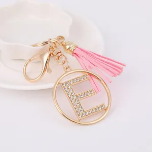 Detail shot of gold rhinestone letter E keychain charm with pink tassel and metal clasp.