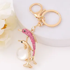 Detailed view of the cute golden dolphin keychain with pink rhinestones and a white pearl bead.