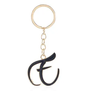 Gold letter keychain detail showcasing elegant black enamel script alphabet charm pendant.
