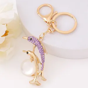 Gold dolphin keychain with purple rhinestones and pearl pendant for bags or keys detail.