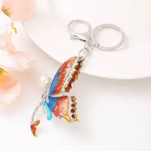Vue détaillée du porte-clés en métal papillon exquis avec émail coloré, strass et perle.