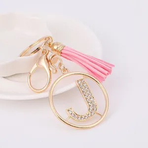 Gold rhinestone letter J keychain with pink tassel, stylish bag charm and ideal gift.