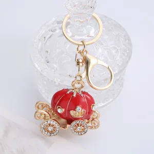 Detailed shot of gold red alloy pumpkin carriage keychain, rhinestone inlaid accessory charm.