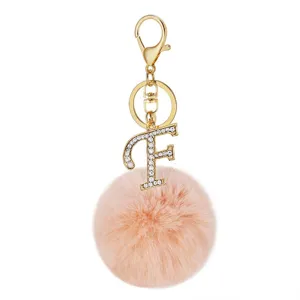 Close-up detail of the gold alloy keychain featuring a sparkling rhinestone letter F and plush pom.