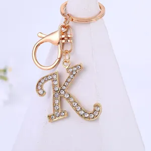 Close-up detail shot of a sparkling rhinestone letter K keychain pendant with a gold finish.