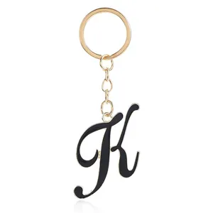 Gold metal keychain with black enamel letter K pendant detail, elegant bag charm accessory.