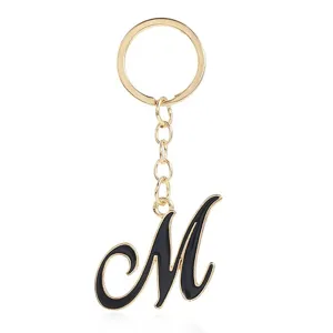Close-up detail of the elegant gold-plated keychain featuring a black enamel letter M pendant.