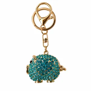 Dettaglio del portachiavi a forma di maialino in strass blu con anello in metallo dorato.