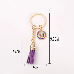 Chic gold-tone keychain with purple tassel and rhinestone letter M pendant. Stylish bag accessory.