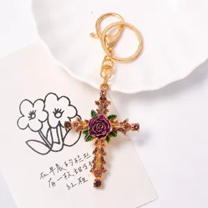 Detailed view of vintage rhinestone rose cross keychain, gold metal finish with purple enamel.