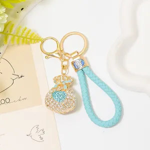 Exquisite rhinestone money bag keychain detail, luxury metal keyring and blue braided leather cord.
