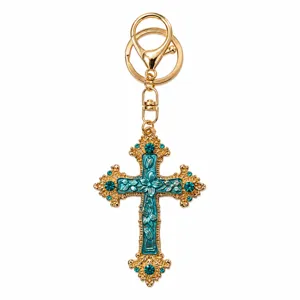 Gedetailleerde close-up van de gouden vintage turquoise emaillen kruis sleutelhanger met strass.